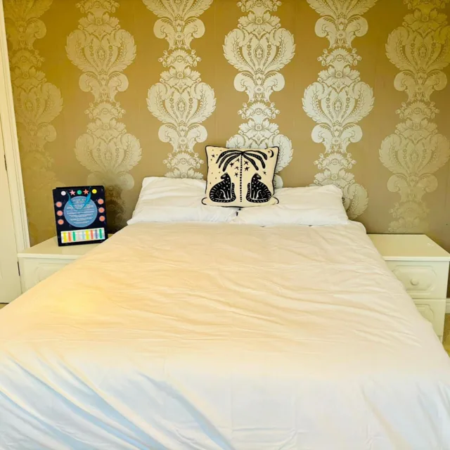 Bedroom with white bedding and patterned wallpaper at Little Ash Farm